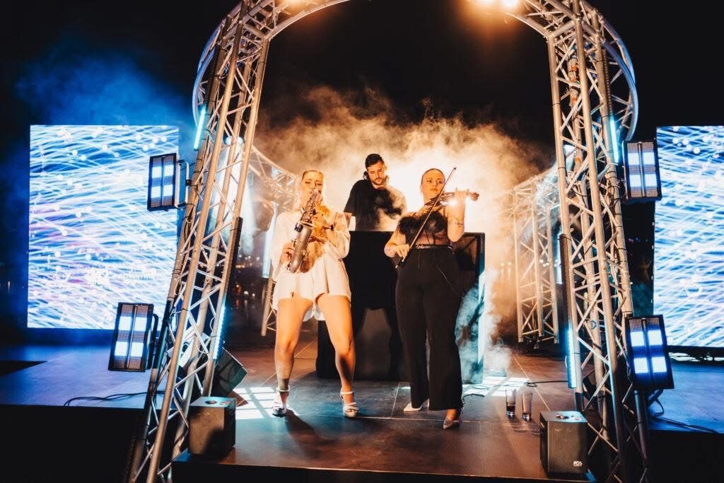 Saxophone and violin performing with the DJ on an LED stage
