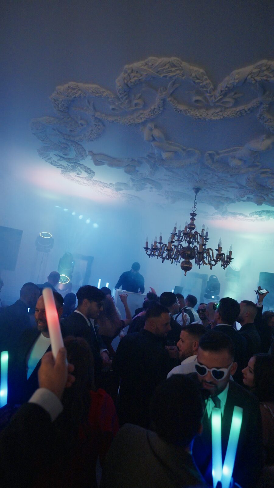 Glow sticks and haze under a frescoed palazzo ceiling