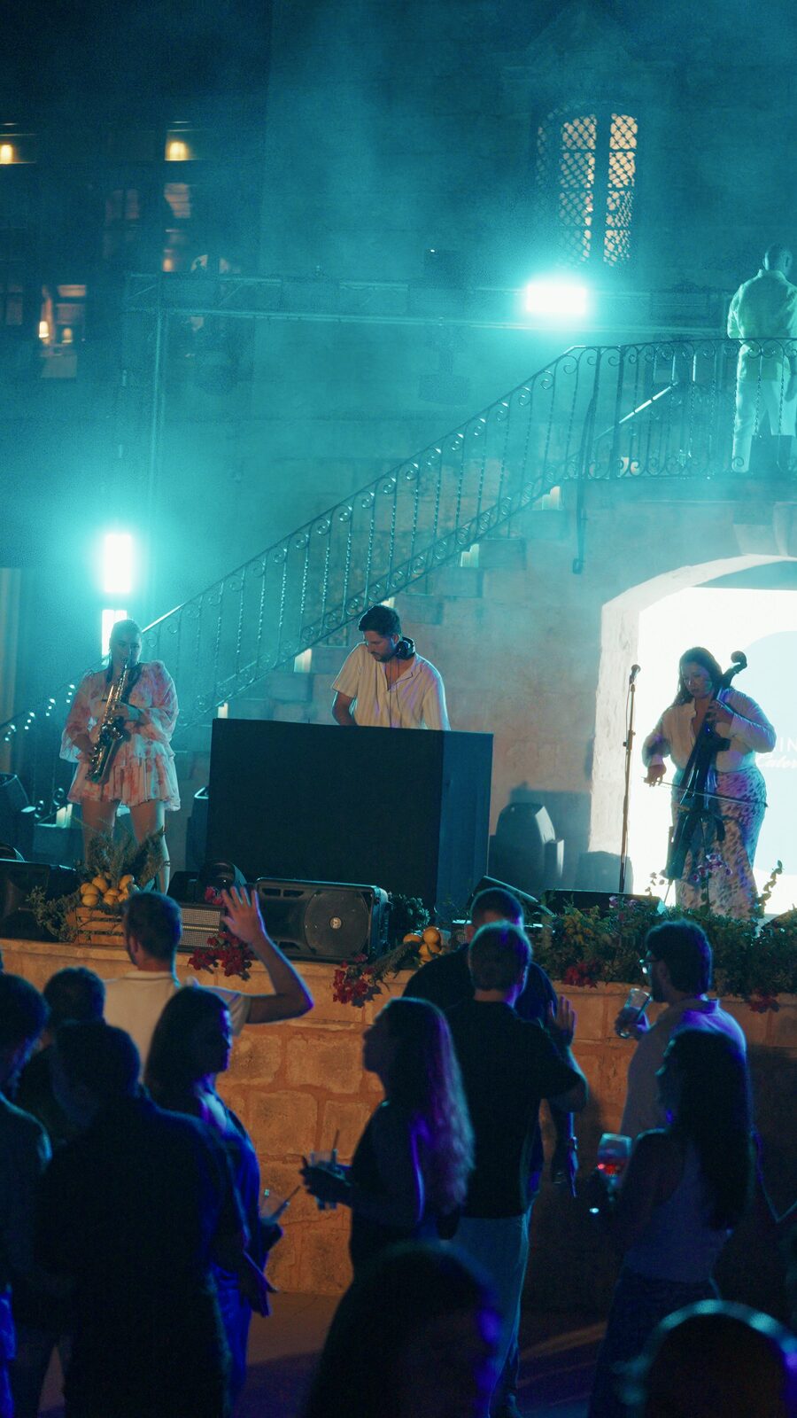 DJ, saxophone and cello on a courtyard stage