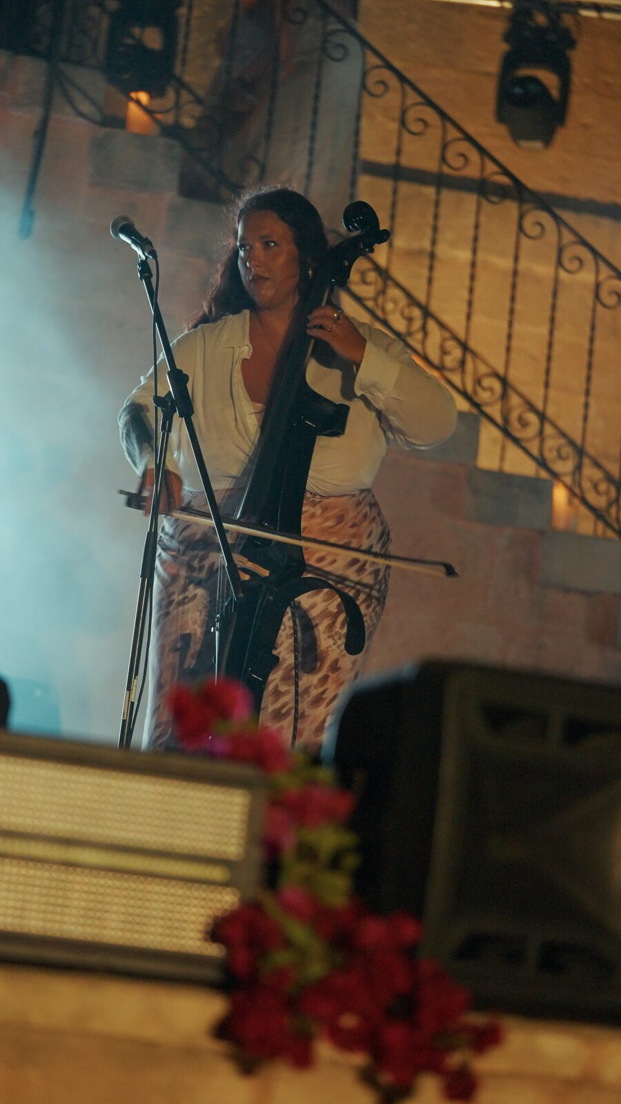 Cellist performing behind the florals and stage wash
