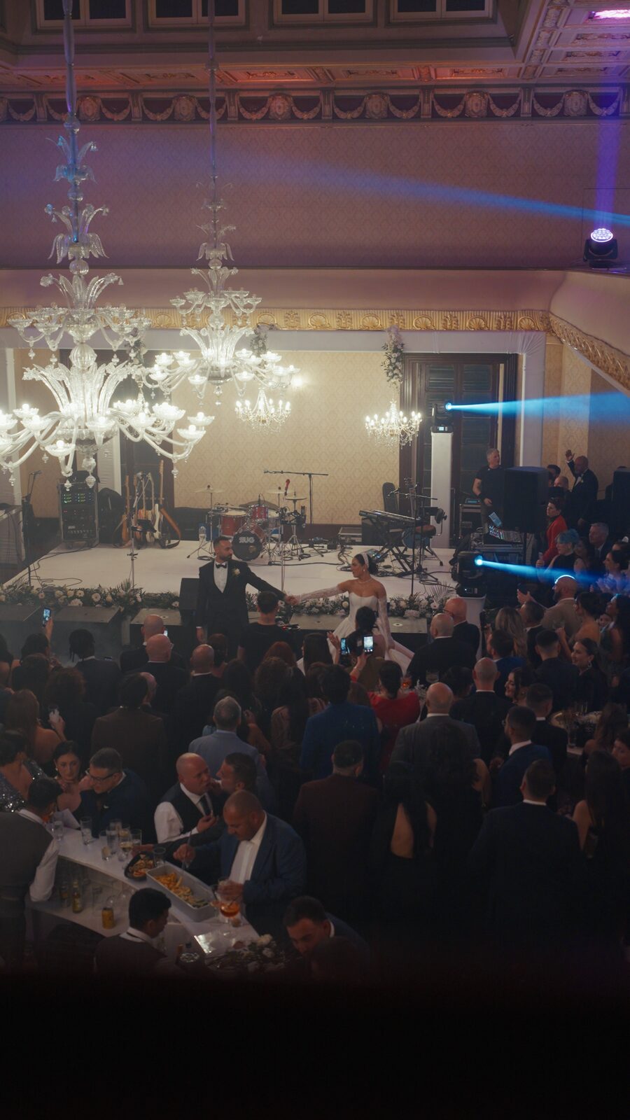 Saxophonist in red performing beneath the ballroom chandeliers
