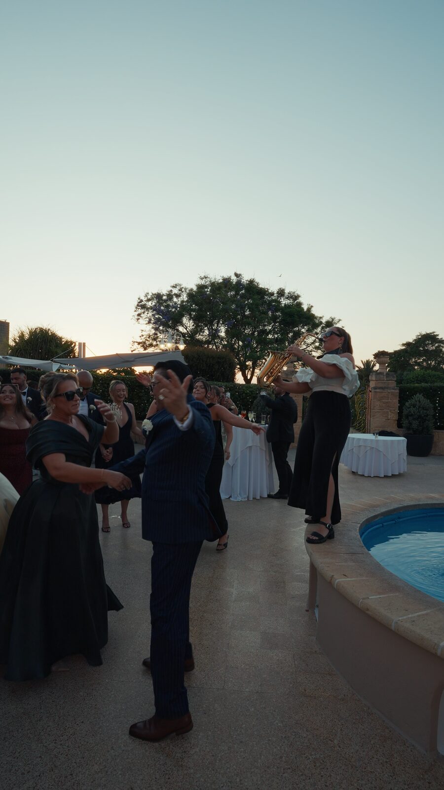 Saxophonist playing poolside at golden hour