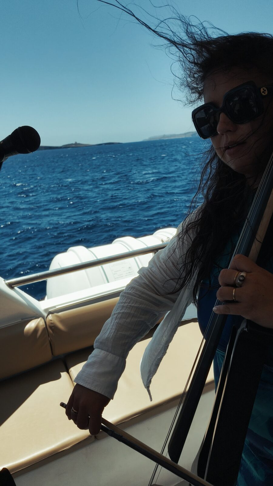 Cellist performing on deck as the boat cruises past Comino